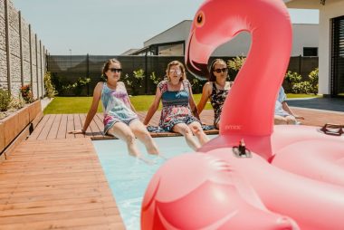 Women enjoying a sunny day by the pool with an inflatable flamingo, epitomizing summer fun.